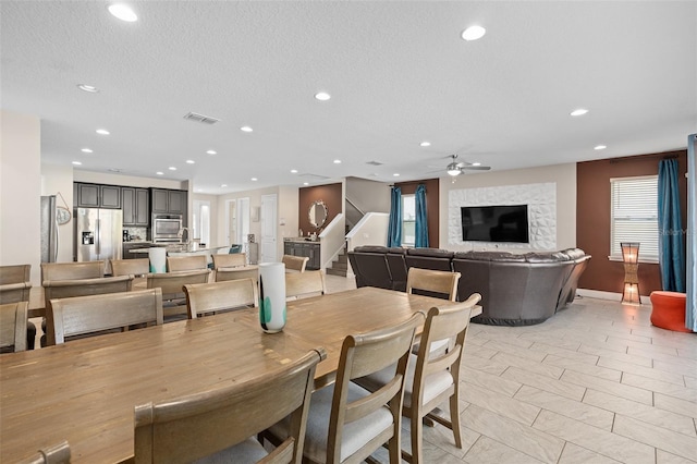 dining room featuring light tile floors, a textured ceiling, ceiling fan, and a healthy amount of sunlight