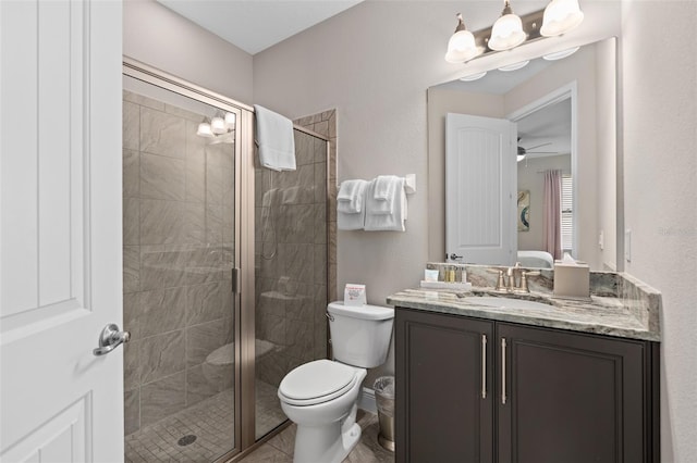 bathroom with toilet, a shower with shower door, ceiling fan, vanity with extensive cabinet space, and tile flooring