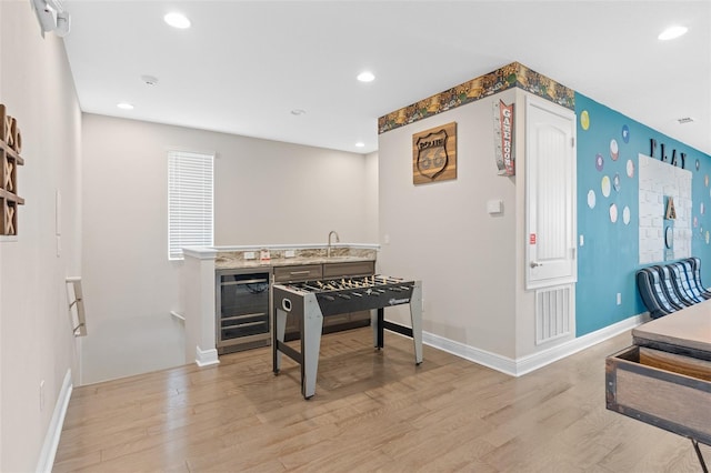 interior space with wine cooler, sink, and light hardwood / wood-style flooring