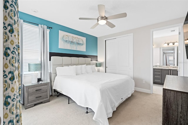 bedroom featuring ceiling fan, a closet, light carpet, ensuite bathroom, and multiple windows