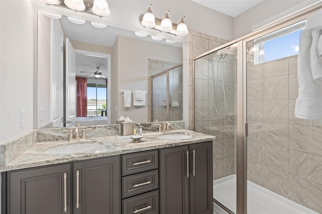 bathroom with a shower with door, a healthy amount of sunlight, ceiling fan, and dual sinks