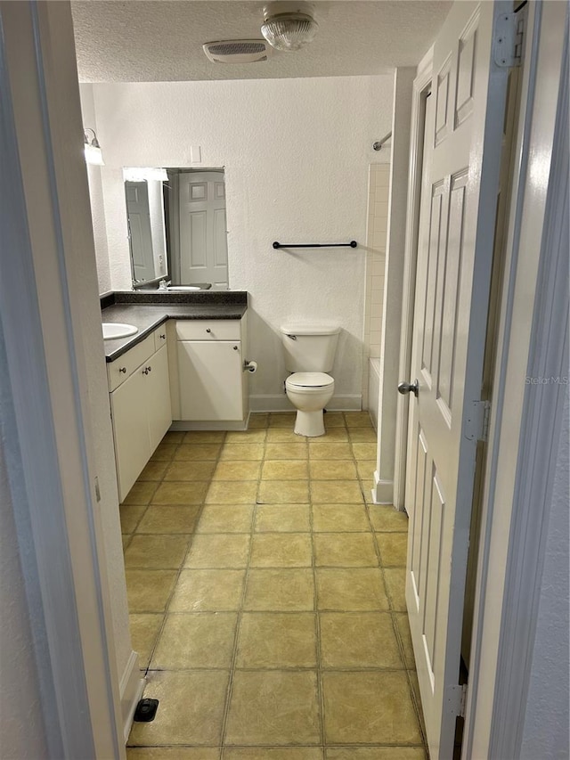 full bathroom with vanity, tile floors, a textured ceiling, toilet, and shower / bath combination