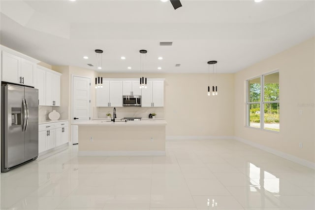 kitchen with a kitchen island with sink, pendant lighting, white cabinetry, tasteful backsplash, and stainless steel appliances