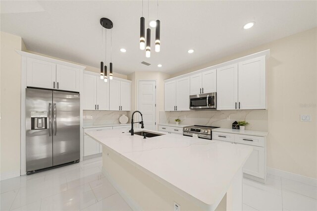 kitchen with appliances with stainless steel finishes, an island with sink, sink, and white cabinets