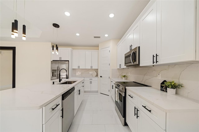 kitchen with an island with sink, hanging light fixtures, stainless steel appliances, and white cabinetry