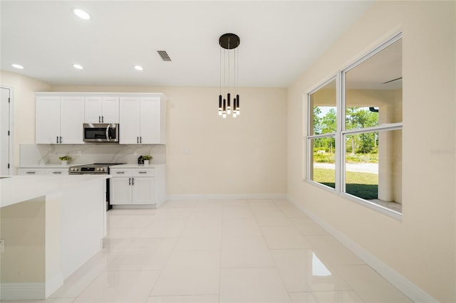 kitchen featuring white cabinets, backsplash, light tile patterned floors, decorative light fixtures, and stainless steel appliances