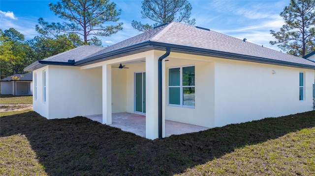 back of property with ceiling fan, a yard, and a patio