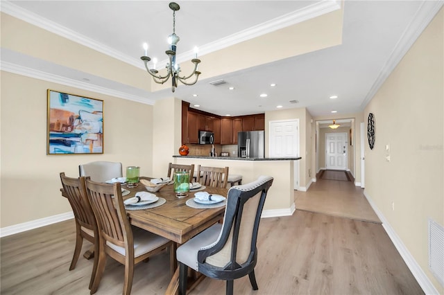 dining space featuring ornamental molding, a notable chandelier, and light hardwood / wood-style flooring