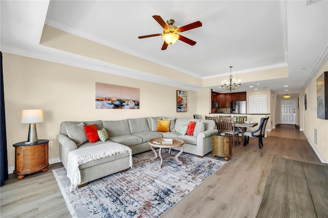 living room with crown molding, a tray ceiling, light hardwood / wood-style floors, and ceiling fan with notable chandelier