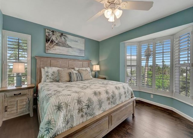 bedroom featuring dark wood-style floors, multiple windows, ceiling fan, and baseboards