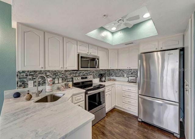 kitchen featuring appliances with stainless steel finishes, backsplash, a sink, and white cabinets