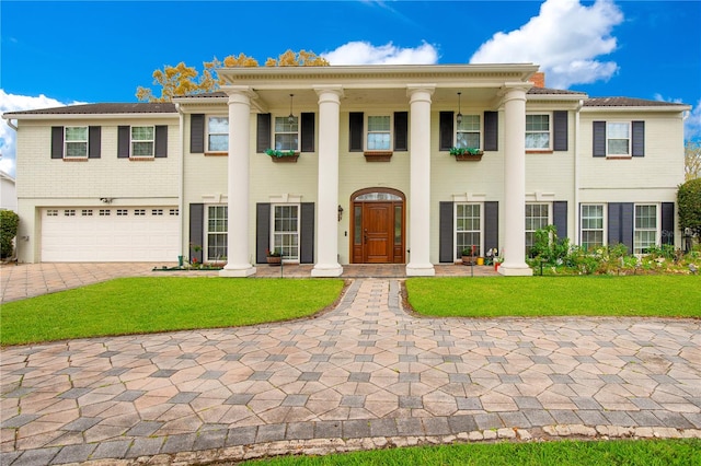 greek revival inspired property featuring a front lawn and a garage