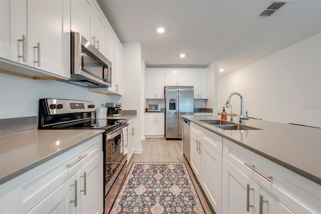 kitchen with white cabinets, light hardwood / wood-style flooring, sink, and stainless steel appliances