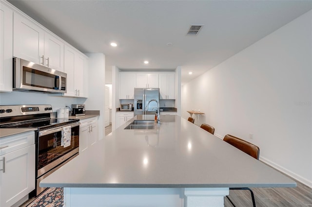 kitchen featuring a center island with sink, stainless steel appliances, and a breakfast bar