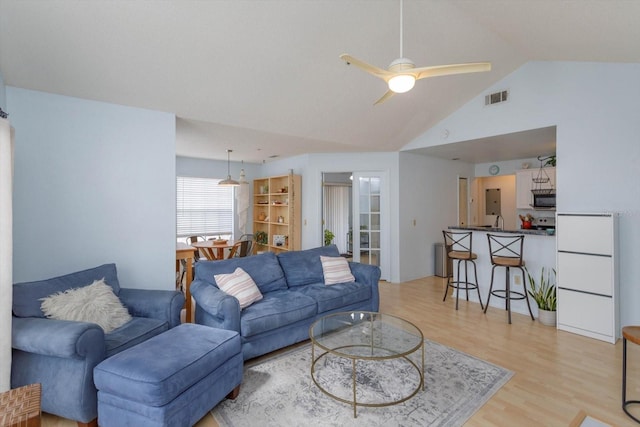 living room featuring ceiling fan, lofted ceiling, and light hardwood / wood-style floors