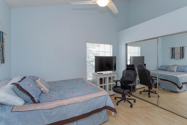 bedroom with a high ceiling, wood-type flooring, ceiling fan, and a closet