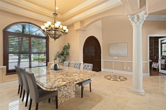 dining space featuring light tile floors, an inviting chandelier, a tray ceiling, and ornate columns