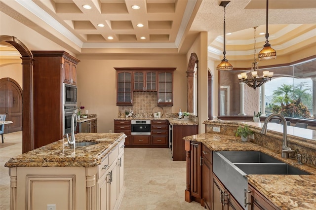 kitchen with light tile flooring, a kitchen island with sink, a notable chandelier, appliances with stainless steel finishes, and tasteful backsplash