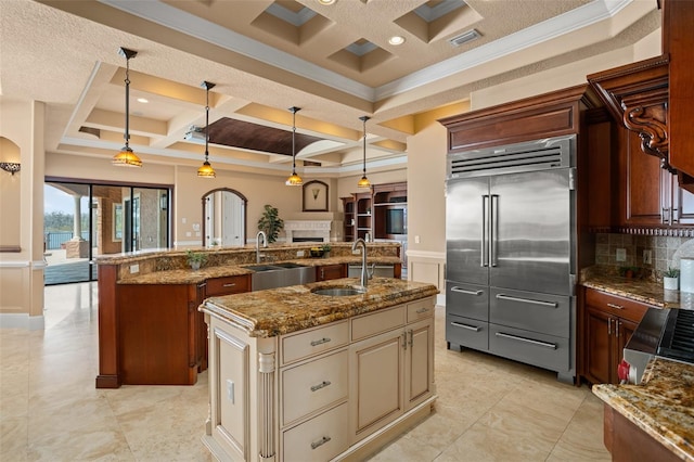 kitchen featuring a kitchen island with sink, sink, coffered ceiling, tasteful backsplash, and stainless steel built in fridge