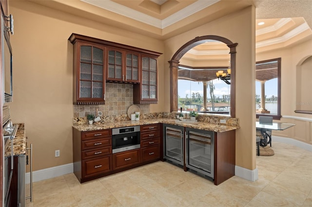 kitchen with an inviting chandelier, tasteful backsplash, a tray ceiling, and wine cooler