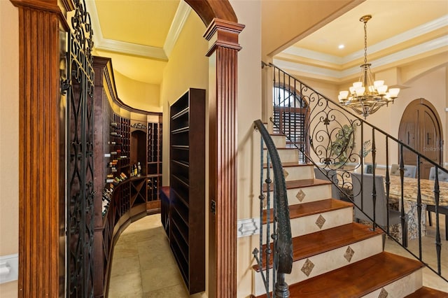 stairs with an inviting chandelier, ornamental molding, decorative columns, and light tile flooring