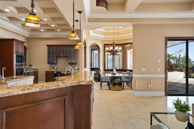 kitchen with light tile floors, hanging light fixtures, coffered ceiling, stainless steel appliances, and an inviting chandelier