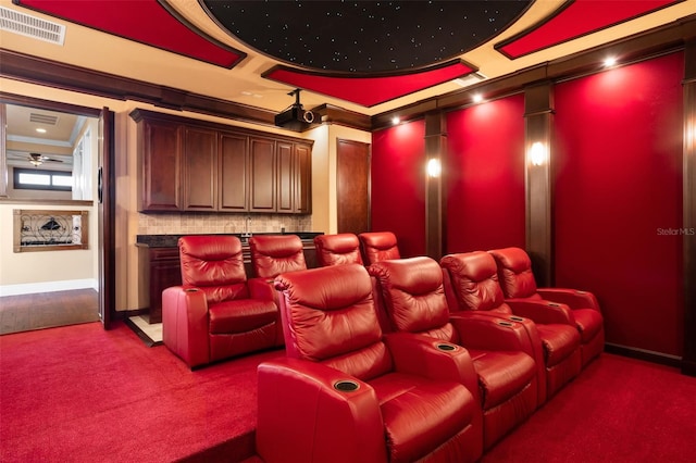 carpeted home theater room with crown molding, a raised ceiling, and ceiling fan