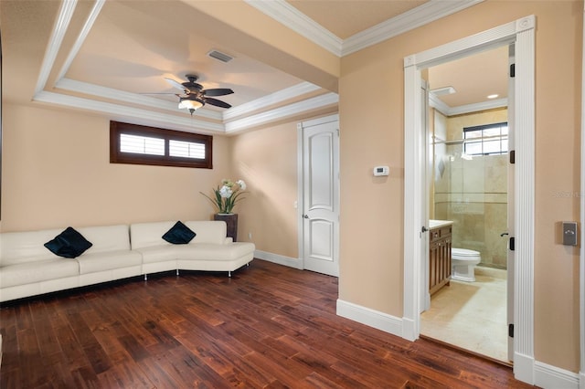 living room with ceiling fan, a tray ceiling, dark wood-type flooring, and ornamental molding