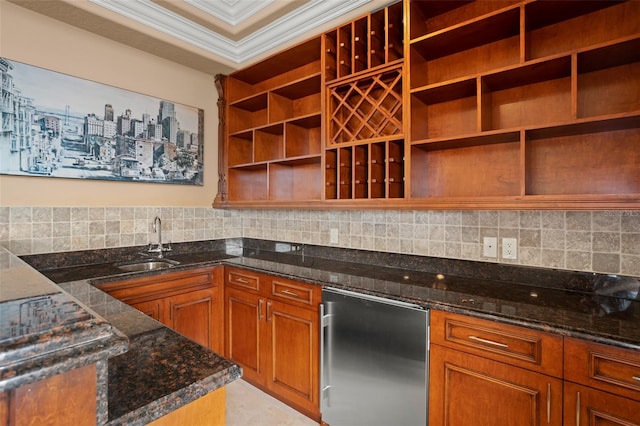 kitchen featuring refrigerator, tasteful backsplash, ornamental molding, dark stone countertops, and sink