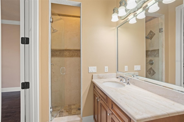 bathroom featuring hardwood / wood-style flooring, a tile shower, oversized vanity, and crown molding