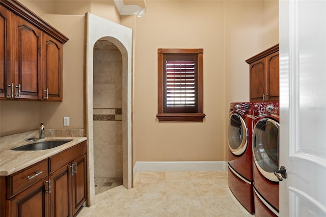 laundry room featuring light tile floors, washing machine and dryer, cabinets, and sink