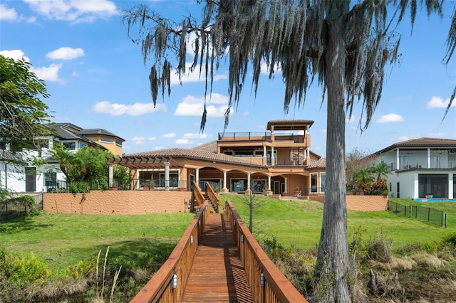 rear view of house featuring a balcony, a pergola, and a lawn