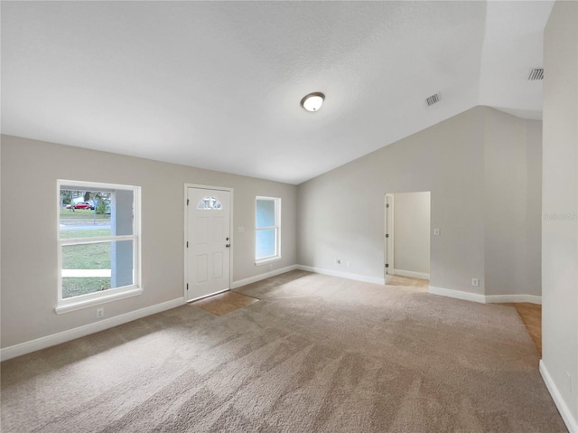 spare room with plenty of natural light, light colored carpet, and vaulted ceiling