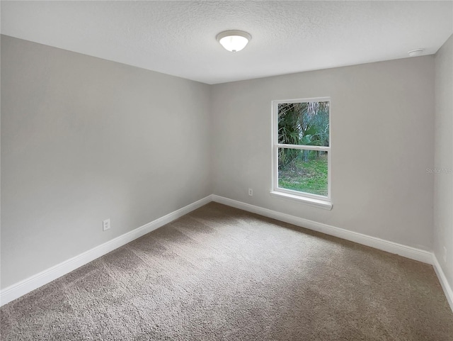 spare room with a textured ceiling and dark carpet