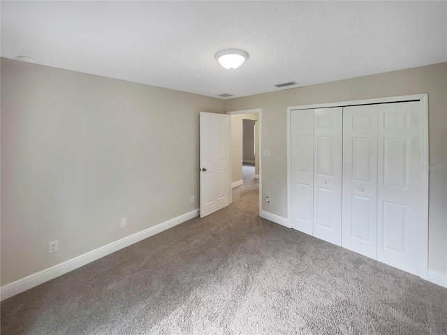 unfurnished bedroom featuring a textured ceiling, a closet, and dark carpet