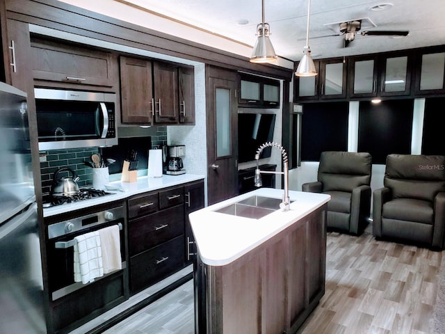 kitchen with backsplash, appliances with stainless steel finishes, light hardwood / wood-style flooring, and ceiling fan