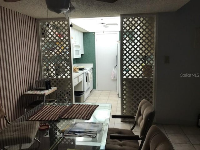 kitchen with white appliances, a textured ceiling, ceiling fan, and light tile floors