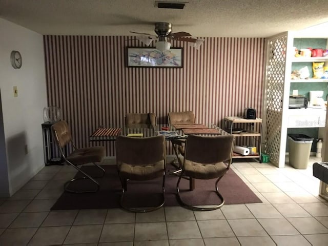 tiled dining space with a textured ceiling and ceiling fan