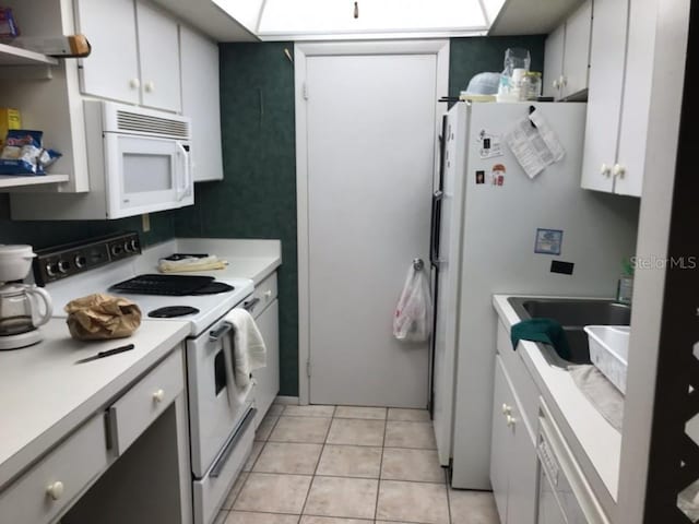 kitchen featuring light tile floors, white appliances, white cabinetry, and sink