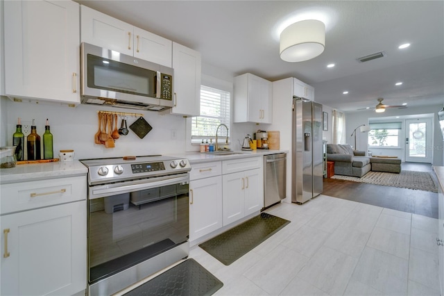 kitchen with white cabinets, a healthy amount of sunlight, ceiling fan, and appliances with stainless steel finishes