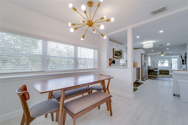 tiled dining area with ceiling fan with notable chandelier and sink