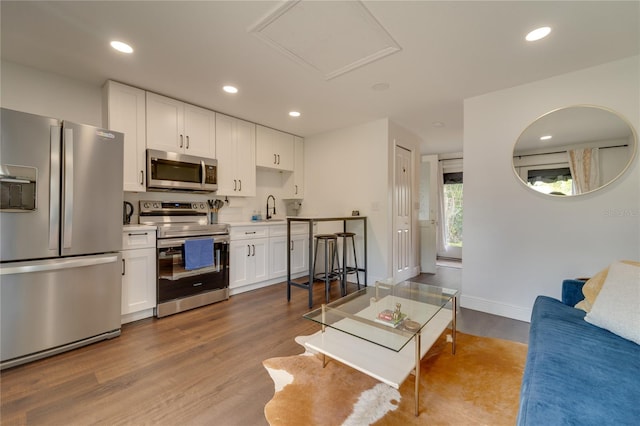 kitchen with white cabinetry, light hardwood / wood-style floors, appliances with stainless steel finishes, and sink