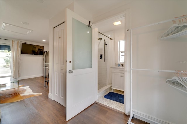 bathroom with a tile shower, a healthy amount of sunlight, and hardwood / wood-style flooring