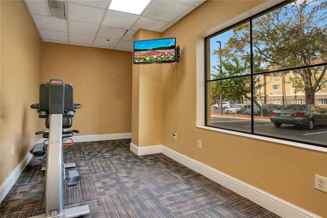 workout area with a paneled ceiling and dark carpet