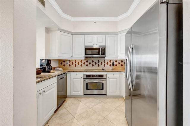 kitchen with tasteful backsplash, white cabinets, light stone countertops, stainless steel appliances, and crown molding