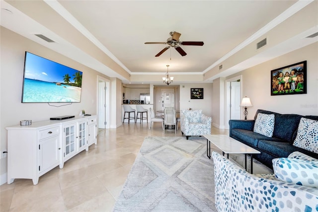 tiled living room with ceiling fan with notable chandelier, a raised ceiling, and crown molding