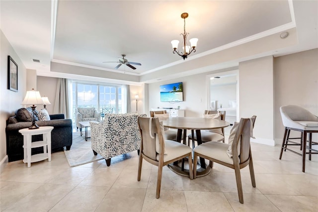 dining space featuring ceiling fan with notable chandelier, a tray ceiling, crown molding, visible vents, and baseboards