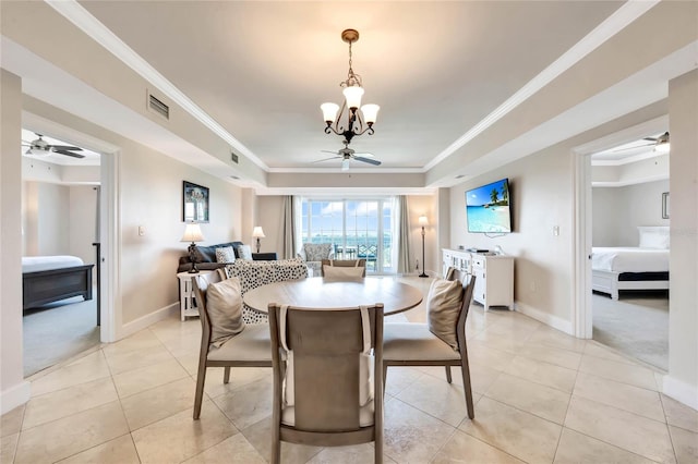 carpeted dining space with ceiling fan with notable chandelier, a tray ceiling, and crown molding