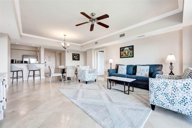 living room featuring ceiling fan with notable chandelier, light tile patterned flooring, and a tray ceiling