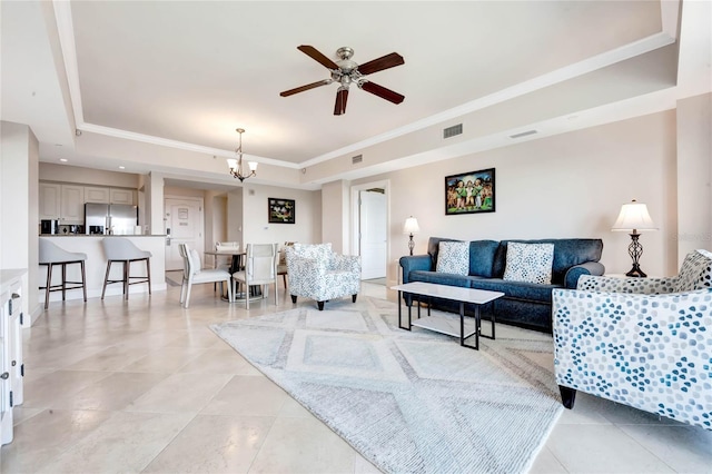 living area featuring ceiling fan with notable chandelier, visible vents, crown molding, light tile patterned floors, and a tray ceiling